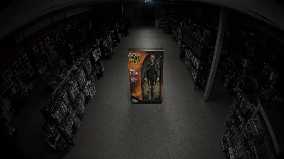 Security camera feed, camera 2: the same store from the ceiling. The costume box stands alone in the middle of the aisle. Nothing moves.